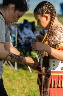 Women adjusting traditional belt on youth girl 