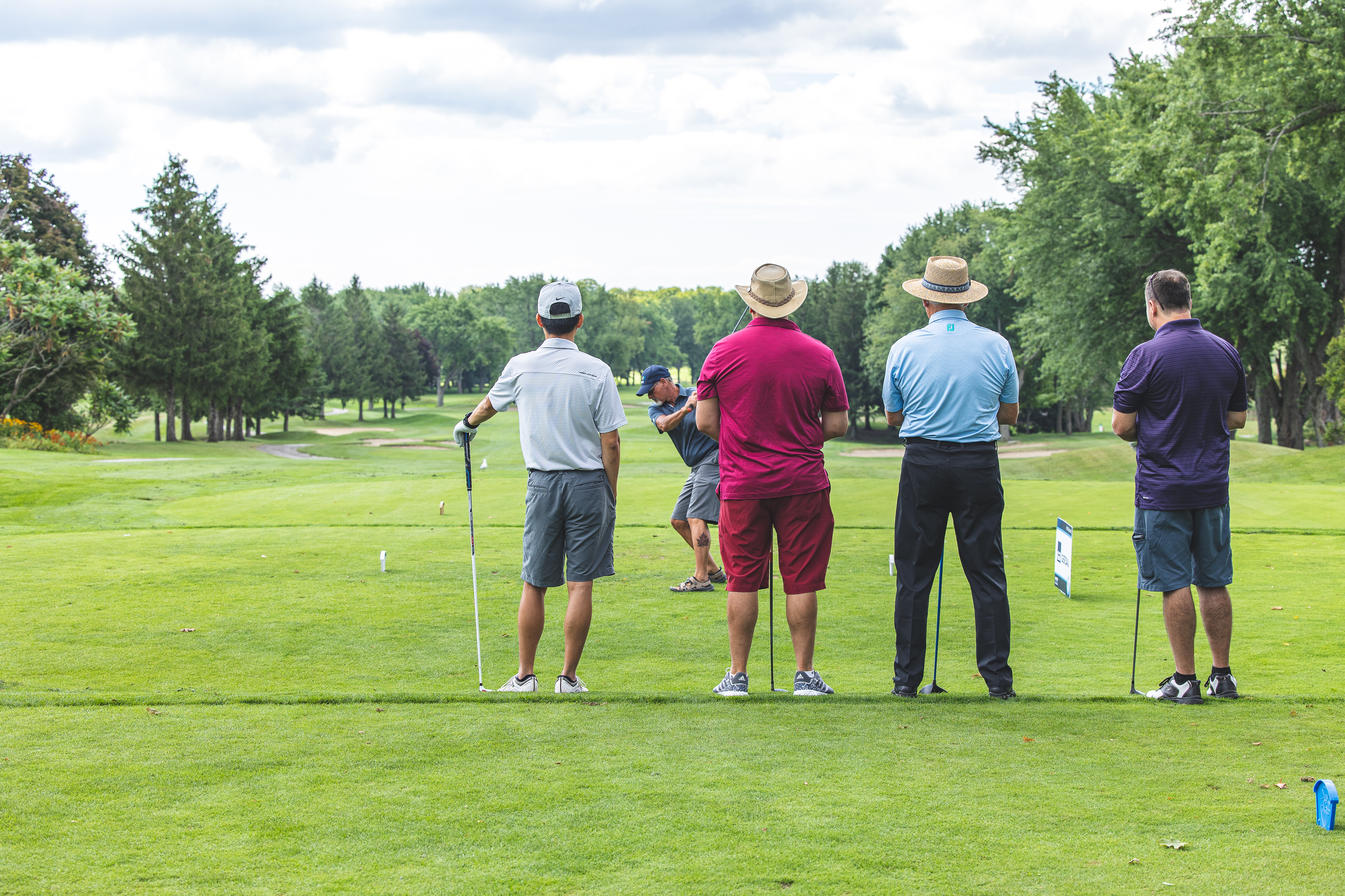 People standing watching a golfer putt