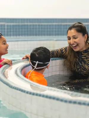 Mom and two kids laughing in pool