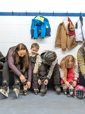 Family sitting on bench lacing up skating in changeroom 