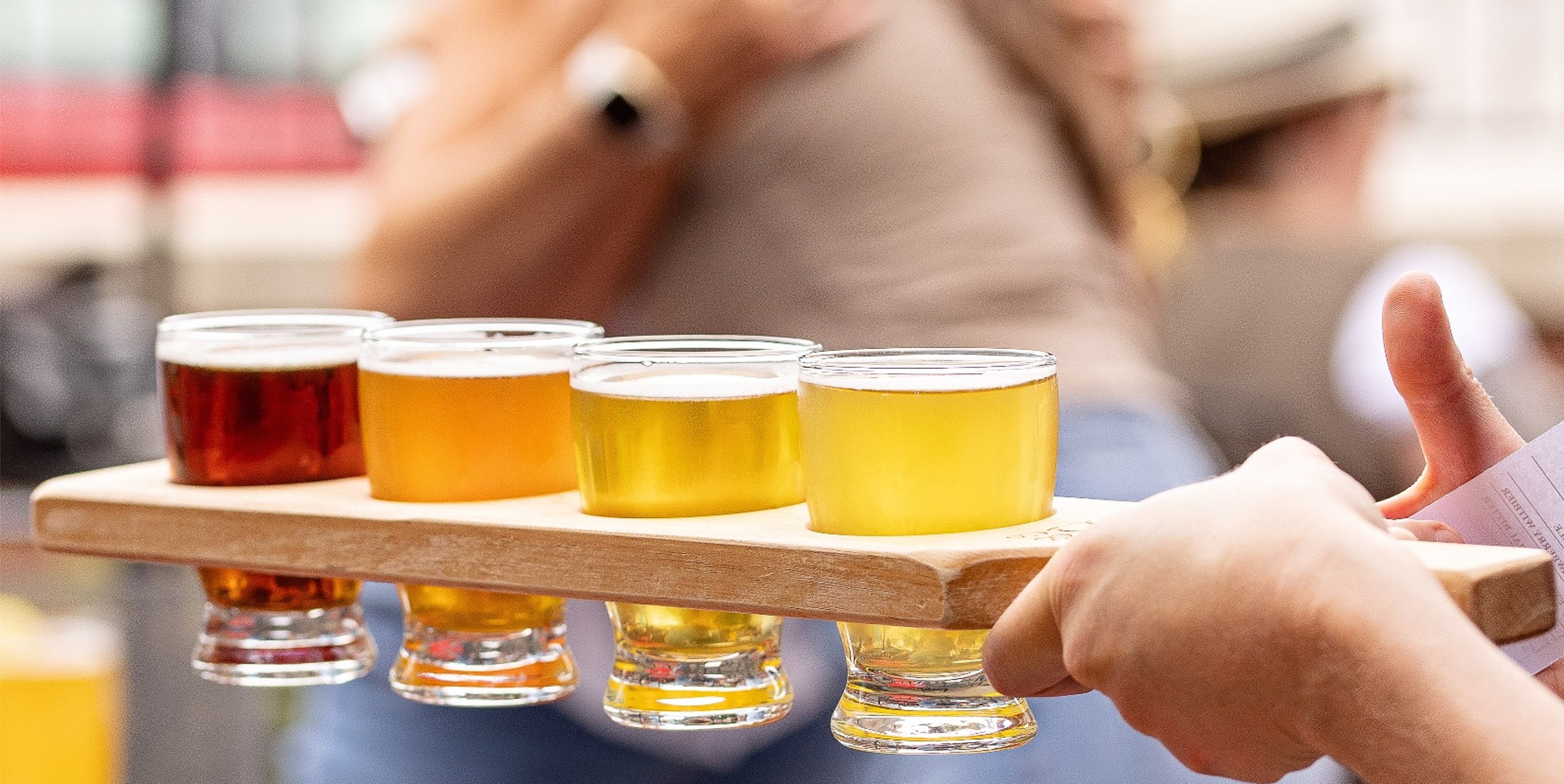 Close up of beer flight with people hugging in back
