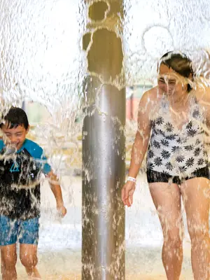 Mom and son laughing while playing in splash pad indoors 