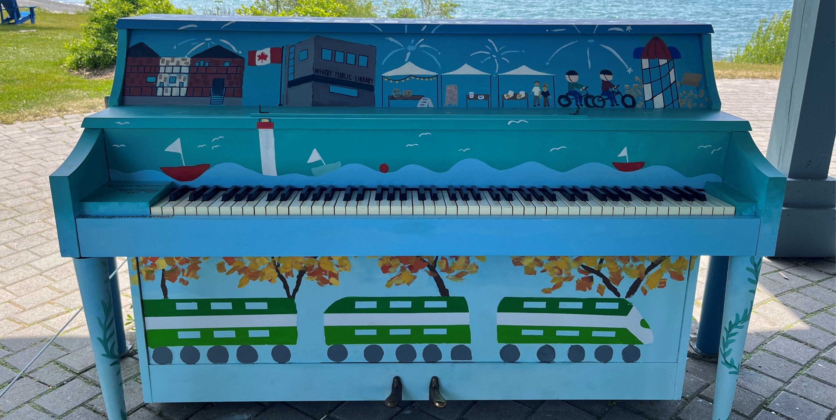 Painted Piano in blue with drawings of Whitby on waterfront