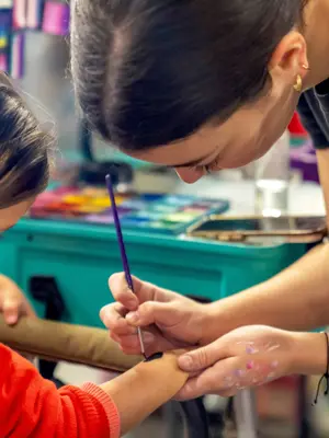 Face painter painting girls hand 