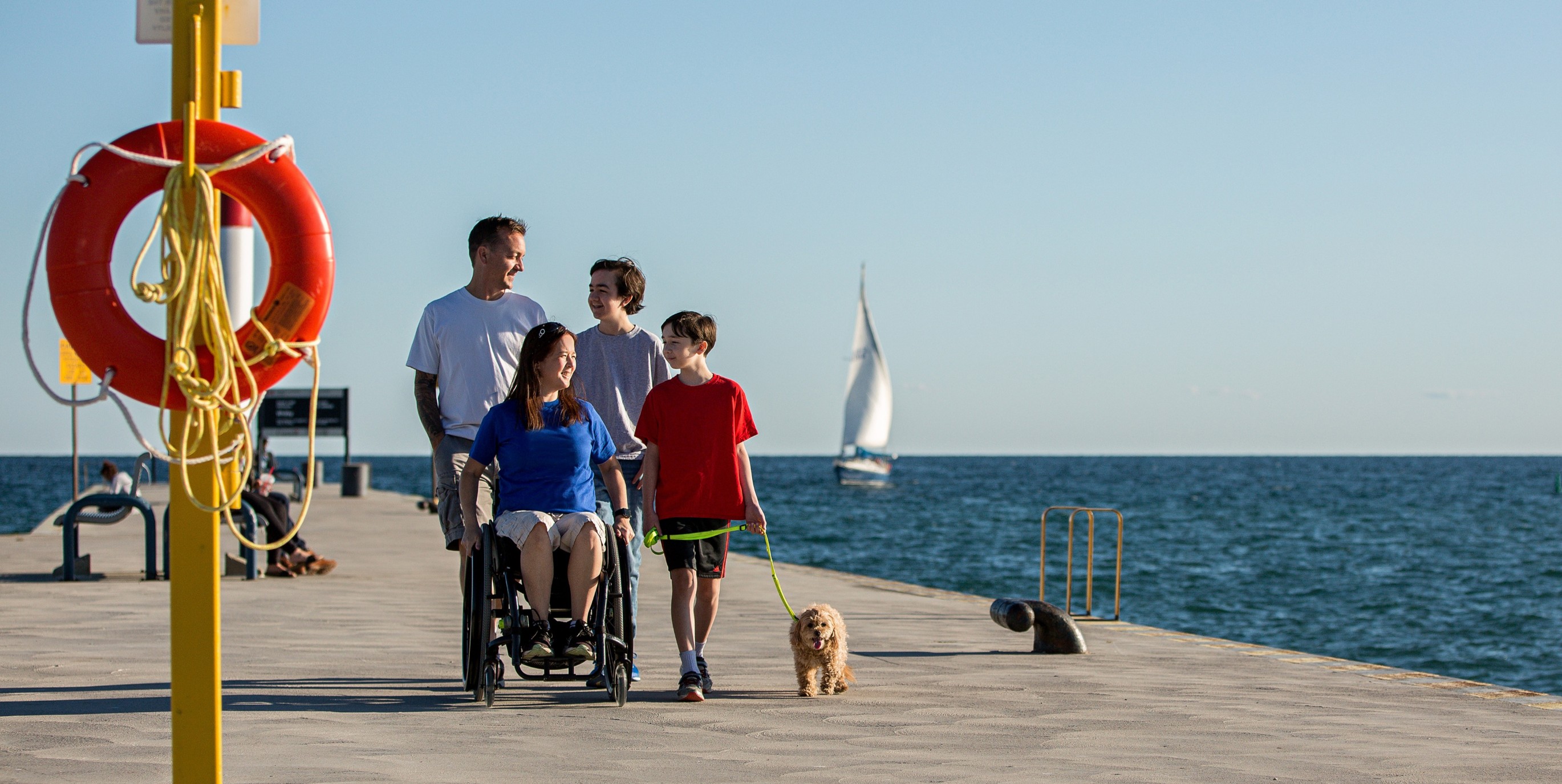 A family of four, one in a wheelchair, on a pier