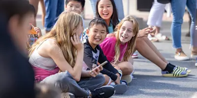 Youth sitting on side of the road at event laughing 