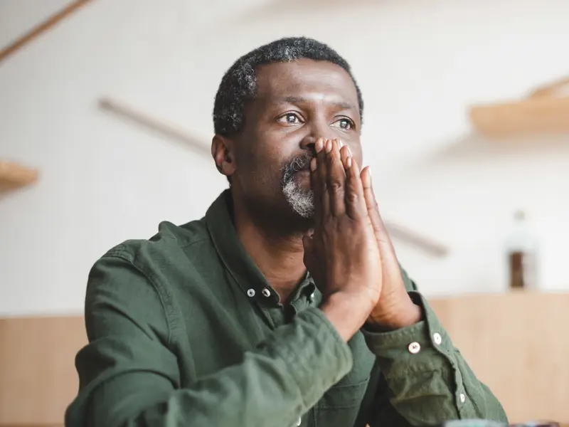 A man deep in thought with his hands in front of his mouth