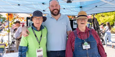 Three volunteers in tent smiling at camera during event 